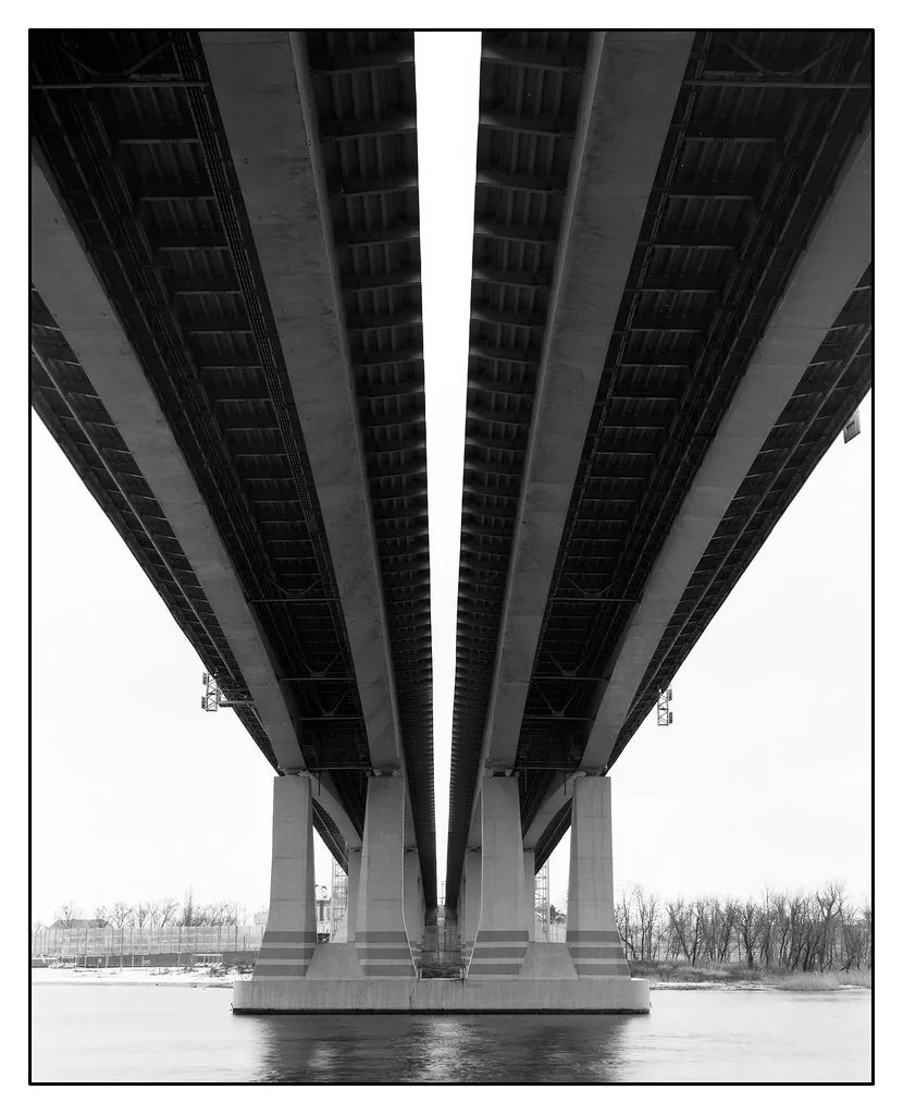 The underside of a bridge receding toward a snowy horizon
